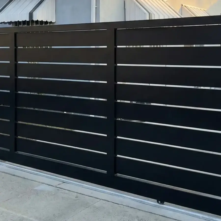 A Customized Black Steel Sliding Gate System On A Concrete Track Featuring Evenly Spaced Horizontal Slats For Privacy In A Residential Front Yard