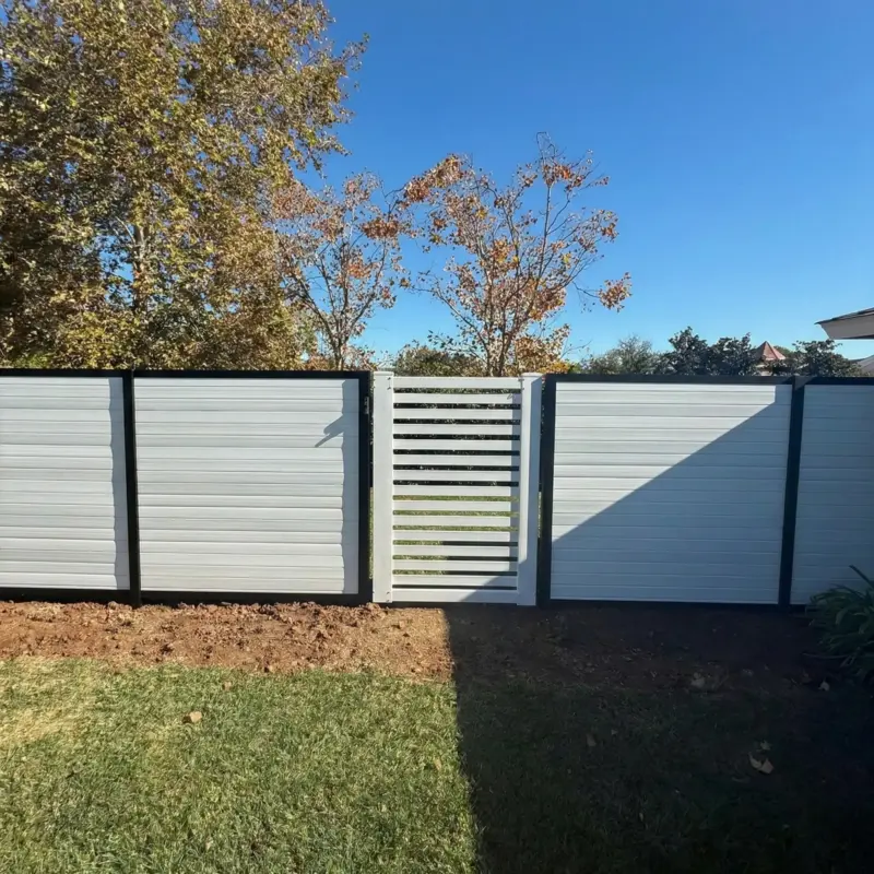 A View From A Sunny Lawn Of A Newly Installed White And Black Horizontal Fence And Gate, With A Van Visible On The Street Behind It