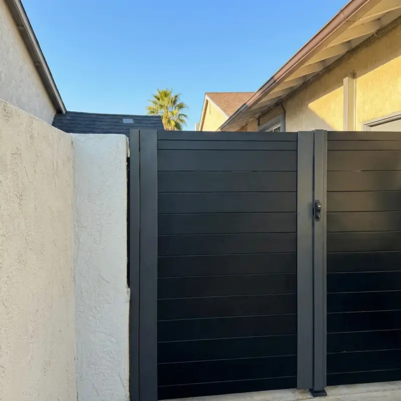 Modern Black Double Driveway Gate Featuring Horizontal Metal Slats And A Central Latch Mechanism