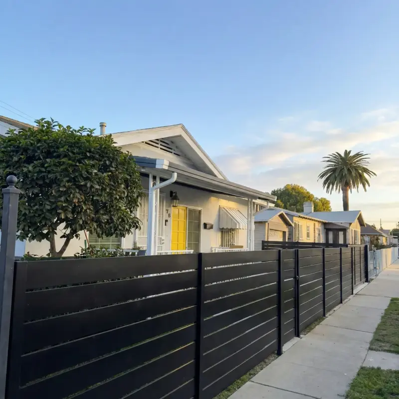 Sleek Modern Privacy Fencing Featuring Clean Black Horizontal Lines, Illuminated By Warm Morning Sunlight To Showcase Residential Curb Appeal