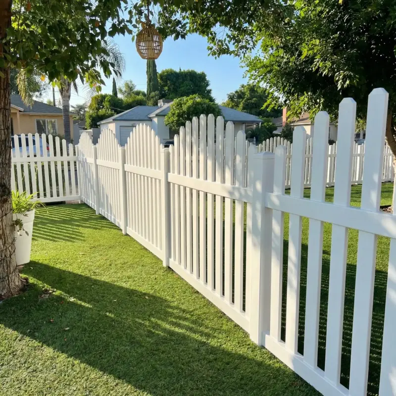 View Of A WellMaintained Backyard Featuring Artificial Grass, A White Fence, And A Yellow Stucco Home